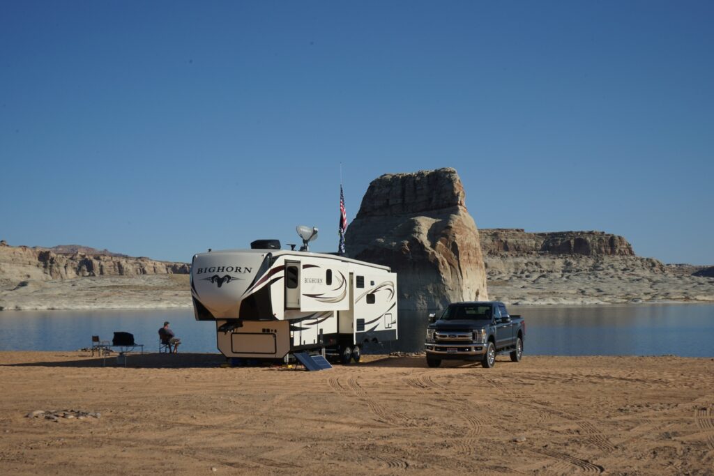 RV and truck next to rocks and water